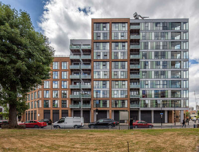 Frontale Ansicht eines modernen Mehrfamilienhauses mit großen Glasflächen und Balkonen.