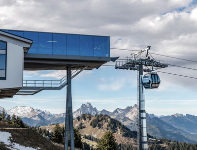 Bergstation mit verglasten Fassaden, die einen weiten Blick auf eine Gebirgskulisse mit schneebedeckten Gipfeln bietet.