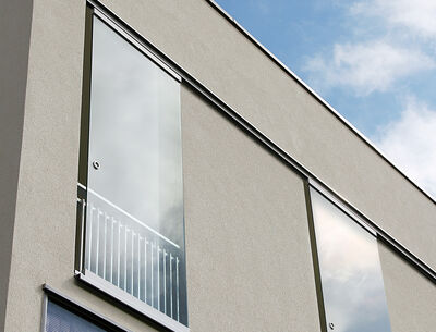 GM Toproll one  Fassade eines modernen Gebäudes mit großen Glasschiebetüren und Balkongeländern.